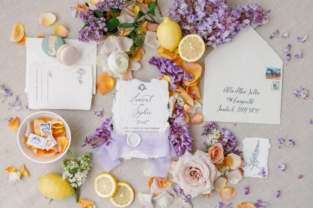 Stunning invitation flat lay filled with purple floral and lemon elements by a Las Vegas Wedding Florist