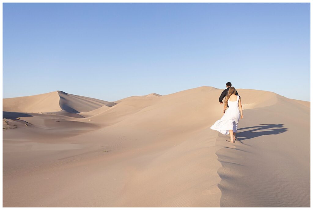 Couple walking along a sand dune for their Las Vegas Engagement Photo